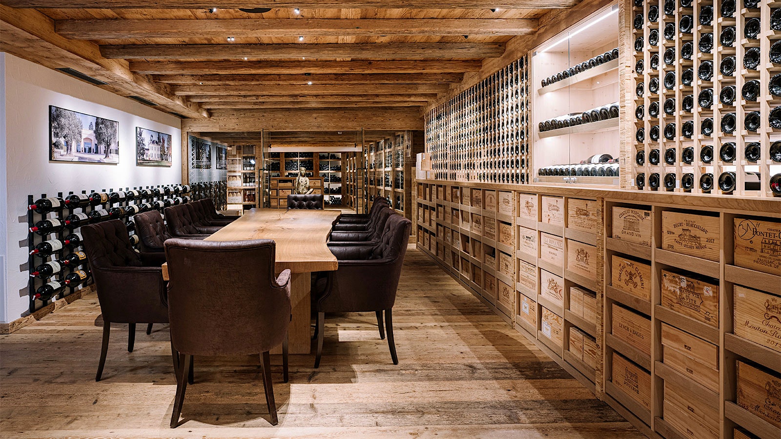 A rustic wood table with leather chairs in a private cellar room at Griggeler Stuba, with a wall lined with racks of bottles and wood bottle crates